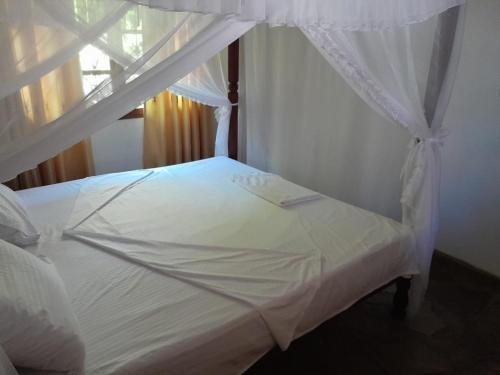 een wit bed met een baldakijn in een slaapkamer bij Lion Garden Villa 7 in Malindi