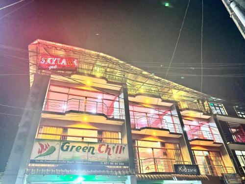 a green city building with neon signs at night at SkyLark Guest House in Nawalapitiya