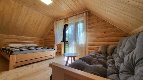 a bedroom of a log cabin with a bed and a window at Котеджі Карпати Fest in Mizhhirya