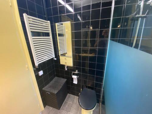 La salle de bains est pourvue d'une douche carrelée de noir et de toilettes. dans l'établissement Casa familiar con piscina, à Pallejá