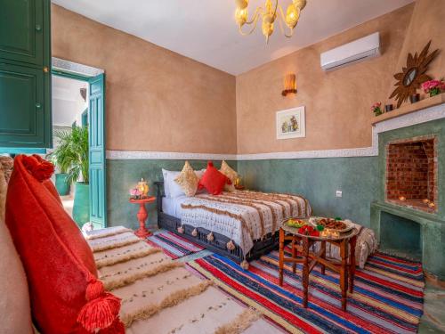een slaapkamer met een bed, een tafel en een open haard bij Riad dar dada&spa in Marrakesh