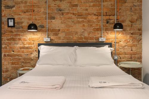 a bed with two towels on it in front of a brick wall at ART B&B in Blackpool