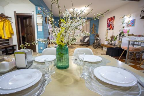 a table with plates and glasses and a vase with flowers at Захарова Оселя in Slavske