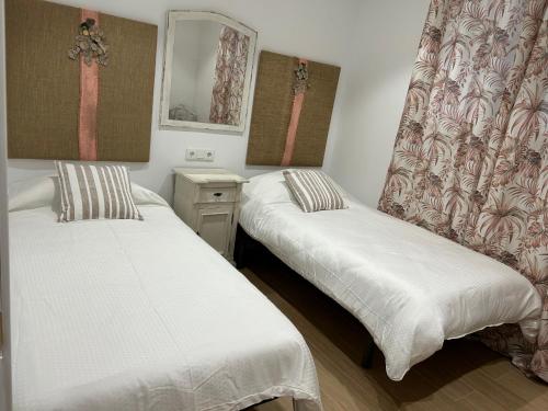 two twin beds in a room with a mirror at AT Osario 12 con Parking in Córdoba