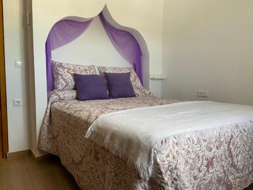 1 dormitorio con 1 cama con cabecero púrpura en La Pequeña Morada, en Arcos de la Frontera