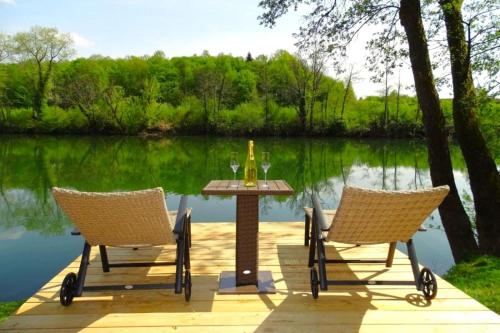 2 sillas y una mesa con copas de vino en una terraza de madera en House Kolpa Paradise Whirlpool and Sauna, en Metlika