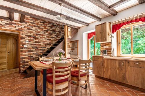 House By The Stream في Avče: مطبخ مع طاولة وكراسي وجدار من الطوب
