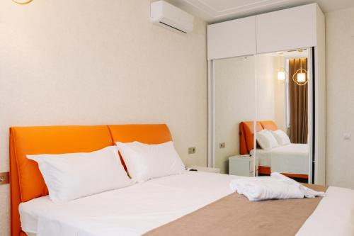 a bedroom with a white bed with an orange headboard at Luxurious Mamu Apartment in Batumi