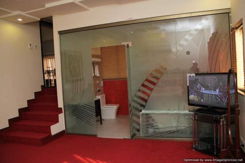 a room with a glass wall with a staircase and a television at Hotel Javson in Sialkot