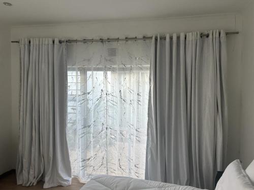 ein Fenster mit weißen Vorhängen im Schlafzimmer in der Unterkunft Urban Fourways Haven in Sandton