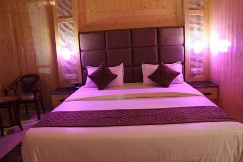 a bedroom with a large white bed with purple pillows at Sukoon Dk in Rudraprayāg