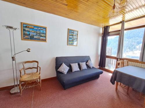 un salon avec un canapé bleu et une chaise dans l'établissement Appartement lumineux sur piste avec balcon et réductions ski - FR-1-165A-182, à Uvernet