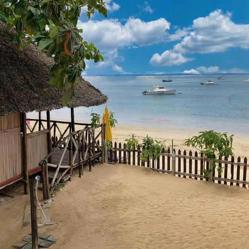 a beach with a fence and a boat in the water at Villa Madirokely in Nosy Be