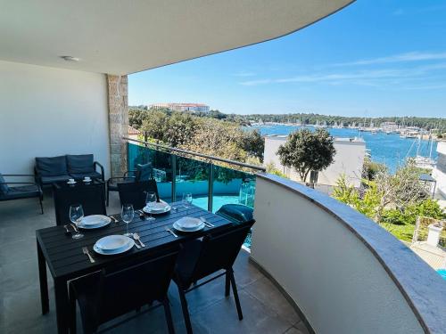 a dining table on a balcony with a view of the water at SeaScape Deluxe Residence in Pješčana Uvala 