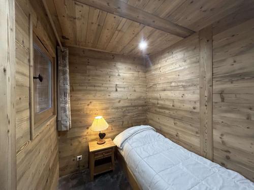 une chambre en bois avec un lit et une lampe sur une table dans l'établissement Appartement 3 pièces proche pistes avec balcon et ski-room - FR-1-180-153, à Méribel