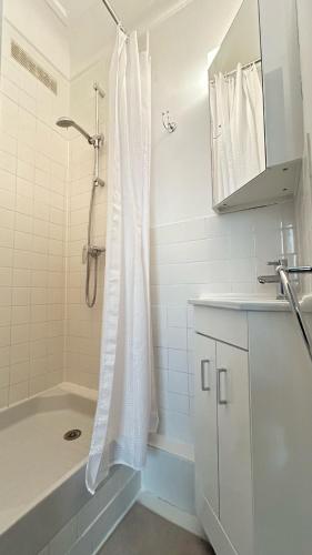 La salle de bains est pourvue d'une douche, d'une baignoire et d'un lavabo. dans l'établissement Coquet Studio Paris 14ème, à Paris