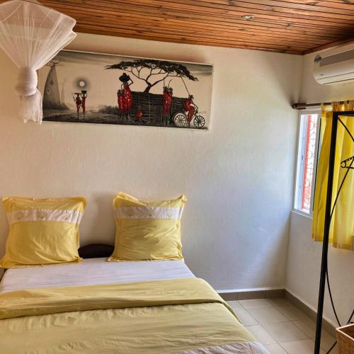 1 dormitorio con 1 cama con una pintura en la pared en Villa Madirokely, en Nosy Be