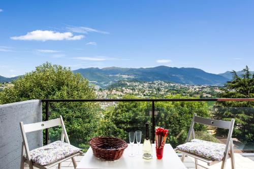 een tafel en stoelen op een balkon met uitzicht bij Pazzallo Panoramica - Happy Rentals in Lugano