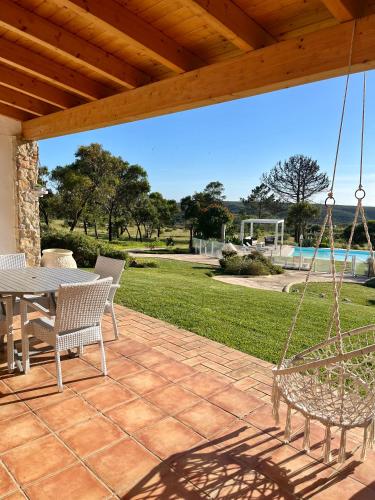 a patio with a swing and a table and chairs at Herdade Monte Do Sol in Aljezur