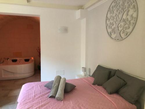 a bedroom with a bed with a pink blanket and a tub at Fernanda's House - Incantevole con idromassaggio su richiesta in Pulsano