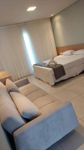 um quarto de hotel com duas camas e um sofá em Apto no Villas BobZ - Barra Grande em Cajueiro