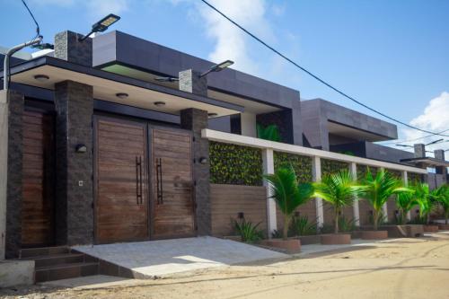 a house with wooden garage doors and palm trees at l'Eldorado in Cotonou