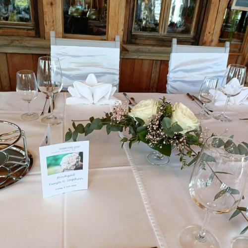 a table with a white table cloth with flowers and wine glasses at Gasthof Sternen Detligen in Detligen