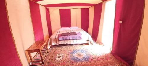 een slaapkamer met een bed in een kamer met rode strepen bij Chigaga Desert Camp in Mhamid