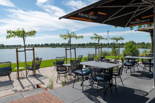 eine Außenterrasse mit Tischen, Stühlen und einem See in der Unterkunft Boutique Hotel de Bungelaer in Beers