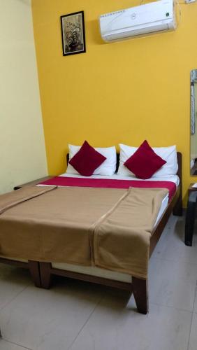 Cama con almohadas rojas en habitación amarilla en Hotel sagar deluxe en Hospet