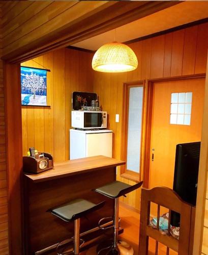 a kitchen with a bar with two stools and a microwave at 百合の家 in Kyoto