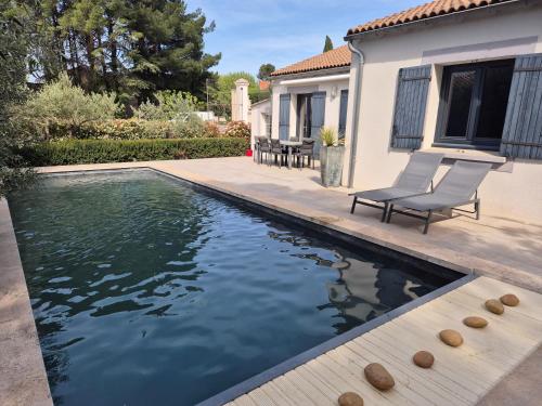 une piscine avec deux chaises à côté d'une maison dans l'établissement Villa avec piscine dans un domaine viticole, à Domazan