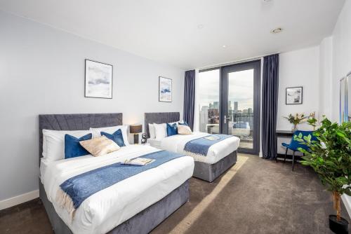 - une chambre avec 2 lits et une grande fenêtre dans l'établissement Luxury & Spacious 2 BR APT with City Views, à Londres