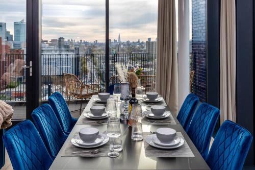 stół z niebieskimi krzesłami i widokiem na miasto w obiekcie Luxury & Spacious 2 BR APT with City Views w Londynie