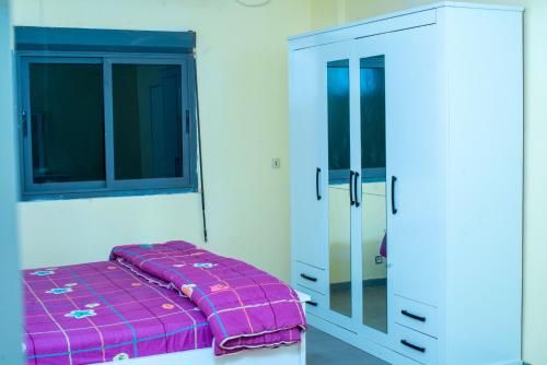 1 dormitorio con 1 cama de color púrpura y armario en Heberease Résidences, en Dakar