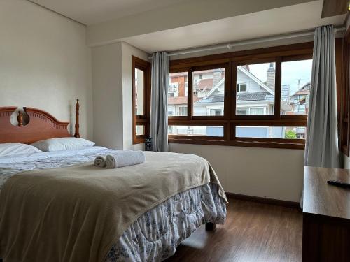 une chambre avec un lit et une grande fenêtre dans l'établissement Apartamento Coração de Gramado, à Gramado