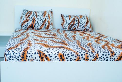 Cama con manta y almohadas de color naranja y blanco en Heberease Résidences, en Dakar