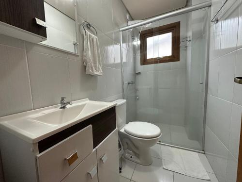 y baño con lavabo, aseo y ducha. en Apartamento Coração de Gramado, en Gramado