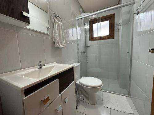 a bathroom with a sink and a toilet and a shower at Apartamento Coração de Gramado in Gramado