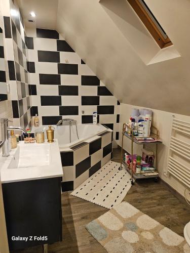 une cuisine avec un mur en damier noir et blanc dans l'établissement Maison Romantique entre deux fleuves chez l'habitant, à Montereau-faut-Yonne