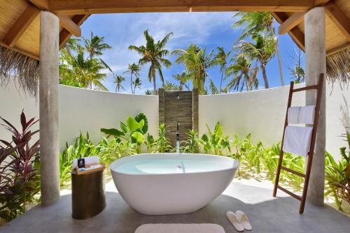 a bath tub on a patio with palm trees at Fushifaru Maldives with 50 percent off on sea plane roundtrip 04 nights & above in Fushifaru