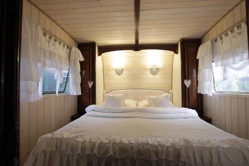 1 cama blanca grande en una habitación con 2 ventanas en Walentynka - romantyczny domek 2-os z prywatnym ogródkiem en Stegna