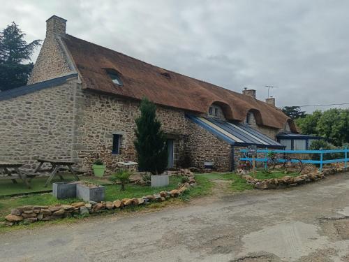 a large brick building with a rusty roof at La Chaumière en Bellevue in Muzillac