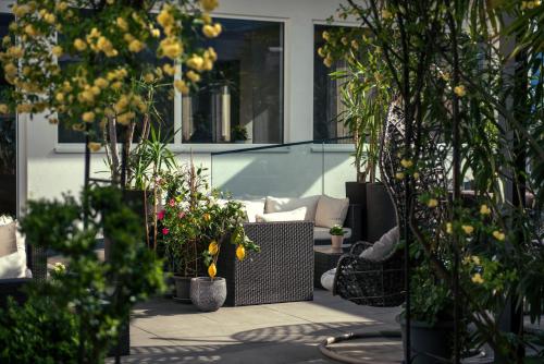 a patio with potted plants and a couch and chairs at Hotel Ladurner in Merano