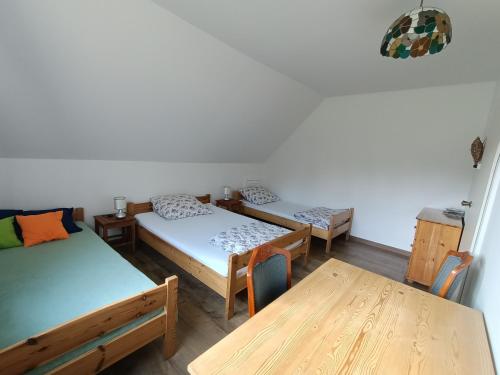 pokój z 3 łóżkami i drewnianym stołem w obiekcie Maślana Chata w mieście Sokolec