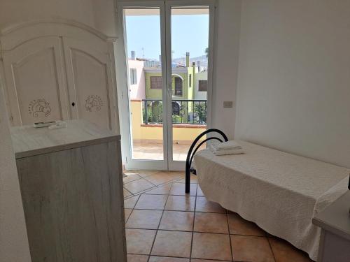 a bedroom with a bed and a large window at ALICE B&B in Villasimius