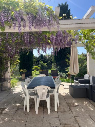 a table and chairs under a pergola with purple flowers at Ibis - villa avec piscine, jardin et parking in Arles