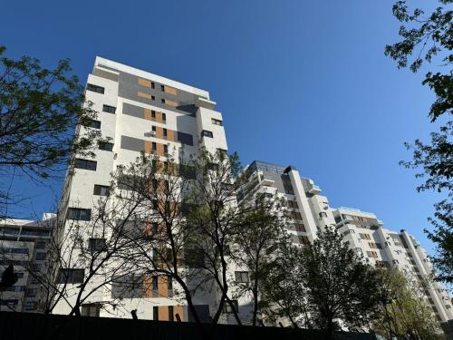 a tall building with trees in front of it at Central Address Towers by GLAM Apartments Bucharest with Parking in Bucharest