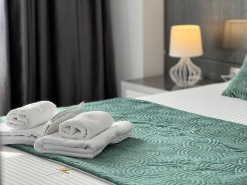 two towels on a bed in a hotel room at Central Address Towers by GLAM Apartments Bucharest with Parking in Bucharest