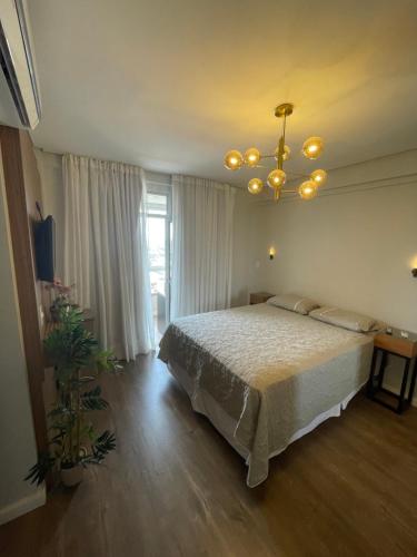 - une chambre avec un lit et un lustre dans l'établissement Apartamento Moderno - Centro Luís Eduardo Magalhães - Mobiliado, à Luís Eduardo Magalhães